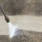 Pressure washing concrete to remove dirt and stains.