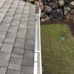 Clean residential white gutter beside a shingle roof.