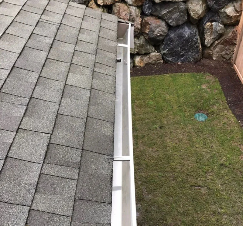 Clean residential white gutter beside a shingle roof.